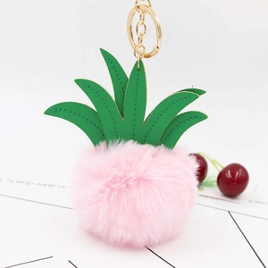 Close-up of pink fluffy pineapple keychain with green faux leather leaves and gold clasp