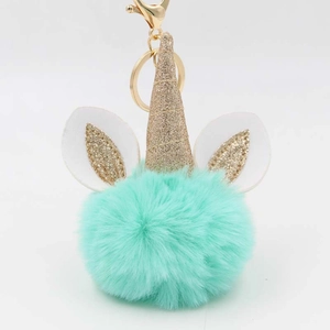 Detail of mint green faux fur unicorn pom pom keychain with gold glitter horn and clasp
