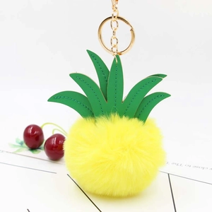 Detail of yellow plush pineapple keychain with green faux leather leaves and golden ring