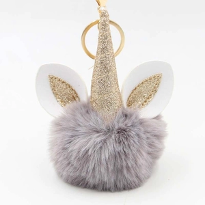 Close-up of a plush unicorn keychain with grey faux fur ball and golden sequin horn