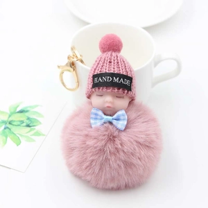 Détail du porte-clés artisanal bébé endormi en peluche avec pompon rose et mousqueton doré