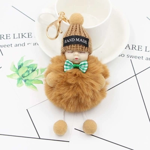 Détail du porte-clés poupée bébé endormi avec boule en peluche et bonnet en tricot