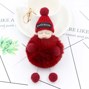 Detailed close-up of a red plush sleeping baby doll keychain with golden lobster clasp