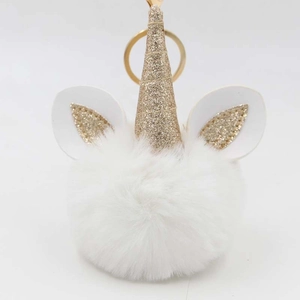 Close-up of fluffy white unicorn plush ball keychain with glittering golden horn and ears