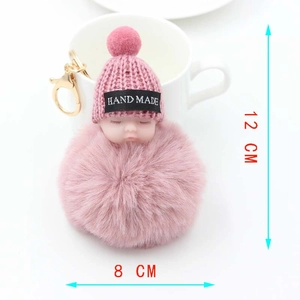 Détail d'un porte-clés bébé peluche rose avec bonnet en tricot à côté d'une tasse à café