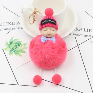 Détail du porte-clés bébé endormi en peluche rose avec pompon sur une tasse en céramique
