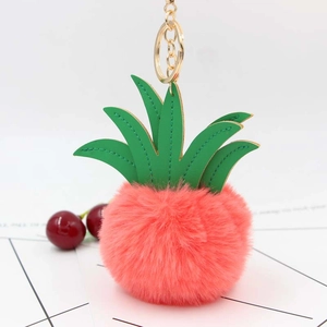 Detail of coral pink pineapple plush keychain with green leather leaves and gold hardware