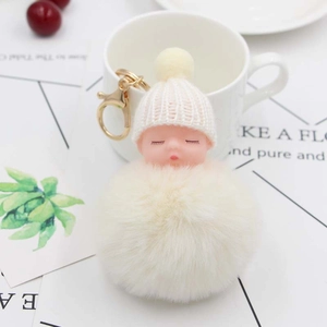 Dettaglio portachiavi neonato che dorme in peluche con pompon beige e moschettone dorato