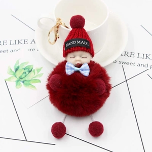 Détail d'un porte-clés bébé peluche avec pompon rouge bordeaux et nœud papillon à carreaux