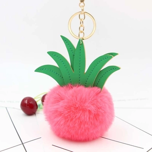 Close-up of pink fluffy pineapple plush keychain with green faux leather leaves