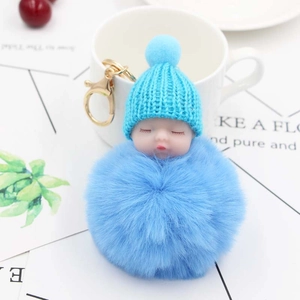 Dettaglio del portachiavi con bambola neonato blu con cappello di maglia e pompon di pelo
