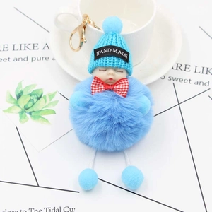 Gros plan du porte-clés poupée bleue avec bonnet fait main et petit nœud papillon à carreaux