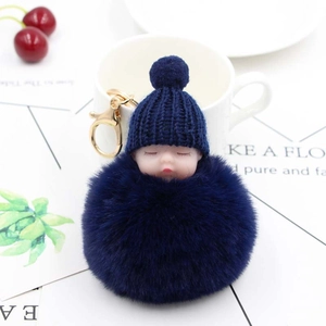 Dettaglio portachiavi pompon con neonato che dorme in blu navy e chiusura dorata