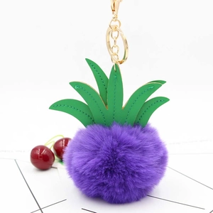 Close-up of fluffy purple pineapple plush keychain with green leaves and gold metal ring