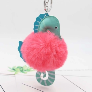 Detail of teal faux leather seahorse keychain with fluffy pink pompom and silver clasp