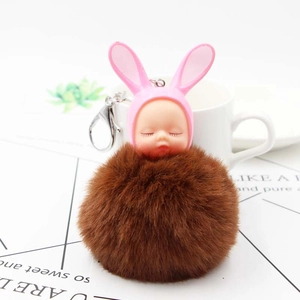 Detailed view of a dark brown fluffy pompom keychain with a sleeping baby and pink rabbit ears