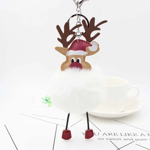 Detailed view of a plush reindeer keychain with a red hat and white fur ball on a desk