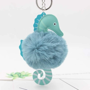 Detailed view of seahorse plush keychain with mint green leather and blue pom-pom ball