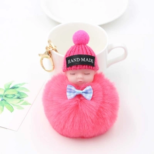 Détail d'un porte-clés bébé en peluche fait main avec pompon rose vif et fermoir doré