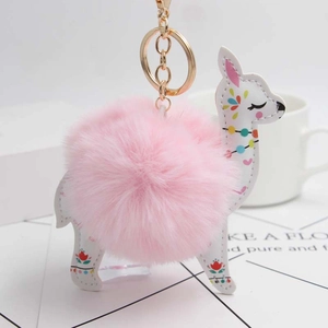 Detail of alpaca leather keychain with floral pattern and fluffy pink pompom accent