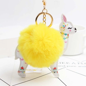 Detailed macro view of yellow pompom alpaca keychain with golden hardware and floral patterns