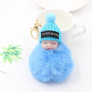 Détail d'un porte-clés poupée endormie bleue avec pompon en fourrure et fermoir doré