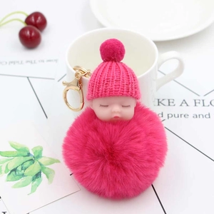 Dettaglio del portachiavi bambola che dorme rosso rosa con pompon e gancio dorato