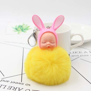Close-up of fluffy yellow faux fur pompom keychain with cute sleeping baby rabbit hood charm