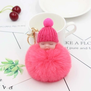 Dettaglio portachiavi pompon rosa con neonato che dorme e gancio in metallo dorato