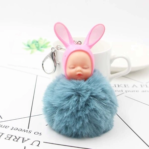 Close-up of pink bunny doll sleeping baby head with a fluffy grey pompom keychain