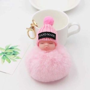 Détail d'un porte-clés bébé endormi en peluche fait main avec bonnet rose et fermoir doré