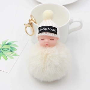 Gros plan du porte-clés bébé endormi en peluche fait main avec pompon et anneau doré