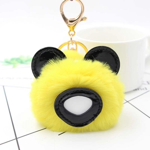 Détail d'un porte-clés panda jaune en fausse fourrure avec boucle dorée et oreilles noires