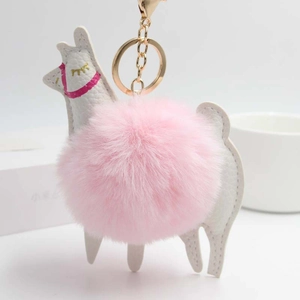 White alpaca keychain with a pink fluffy fur ball and gold metal ring on a white gift box