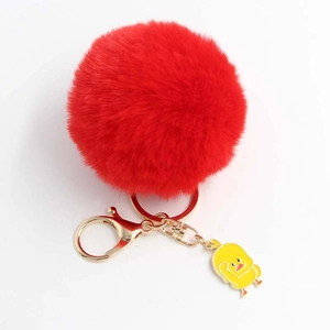 Dettaglio del portachiavi con pompon rosso morbido, anello dorato e ciondolo a forma di anatra