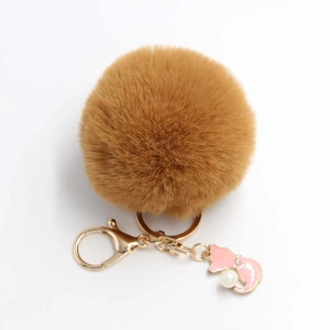 Detail of soft brown faux fur pom pom keychain with a pink cat charm and pearl