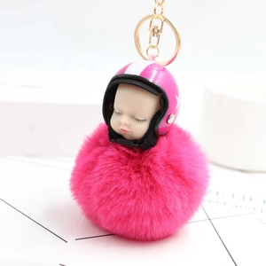 Close-up of fluffy magenta pom-pom keychain with baby sleeping in pink helmet