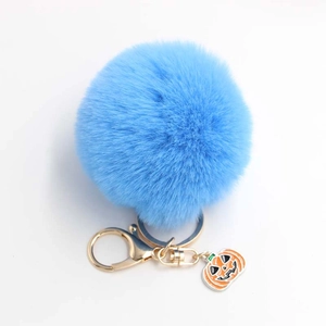 Détail d'un porte-clés pompon bleu en fausse fourrure avec breloque citrouille et fermoir doré