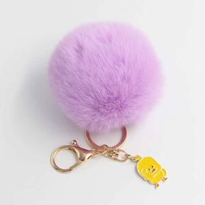 Dettaglio portachiavi pompon viola con ciondolo a forma di anatra gialla e gancio dorato