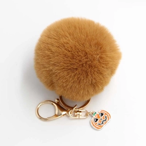Détail d'un pompon en fausse fourrure marron avec anneau doré et pendentif citrouille