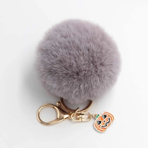 Vue détaillée du porte-clés pompon gris avec breloque citrouille et fermoir doré