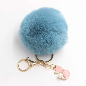 Close-up of light blue fluffy pompom keychain with pink fox charm and white pearl