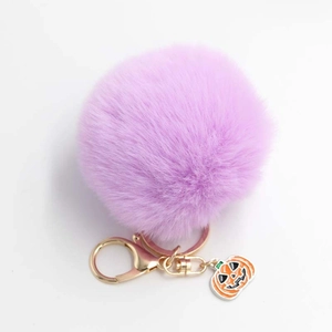 Détail d'un porte-clés pompon en fausse fourrure violette avec anneau doré et citrouille