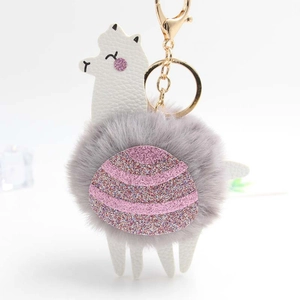 Cute alpaca plush keychain with grey pompom body and pink sequin accents on white leather