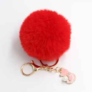 Close-up of red fluffy faux fur keychain with gold cat charm and pearl accents