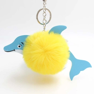 Cute dolphin plush pompom keychain with yellow fur ball and blue textured accents