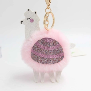 Detail of pink alpaca plush keychain with gold lobster clasp and purple glitter saddle