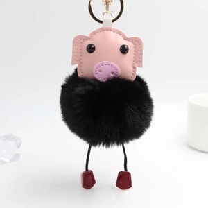Détail d'un porte-clés cochon avec tête en cuir rose et pompon en fausse fourrure noire douce