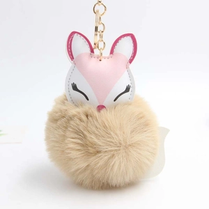 Close-up of sleeping fox plush keychain with soft brown faux fur ball and gold metal hook