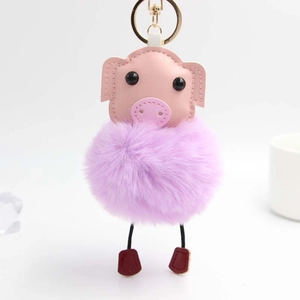 Détail d'un porte-clés cochon en peluche avec boule de fourrure violette et fermoir doré